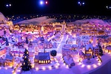An aerial shot of a large model gingerbread town, with working lights glowing against mock snow.