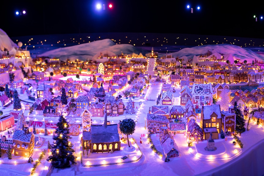 An aerial shot of a large model gingerbread town, with working lights glowing against mock snow.