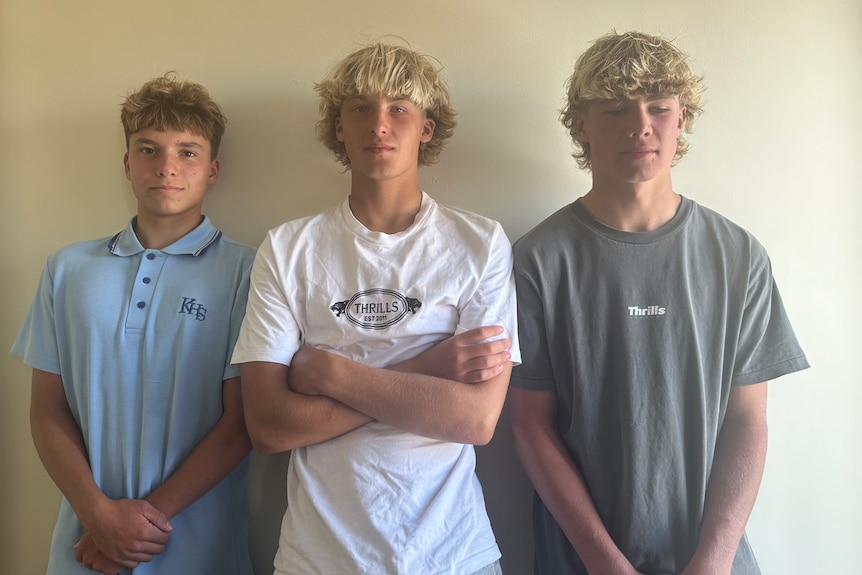 three teenage boys against white wall
