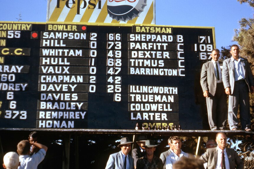 A historic photograph of a manual cricket scoreboard.