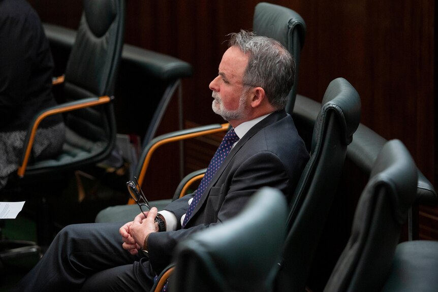 A side-on photo of David O'Byrne sitting by himself in Parliament.
