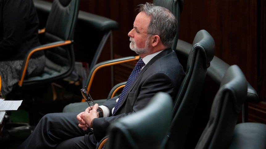 A side-on photo of David O'Byrne sitting by himself in Parliament.