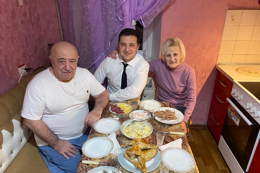 three people sit at at able covered in dishes of food