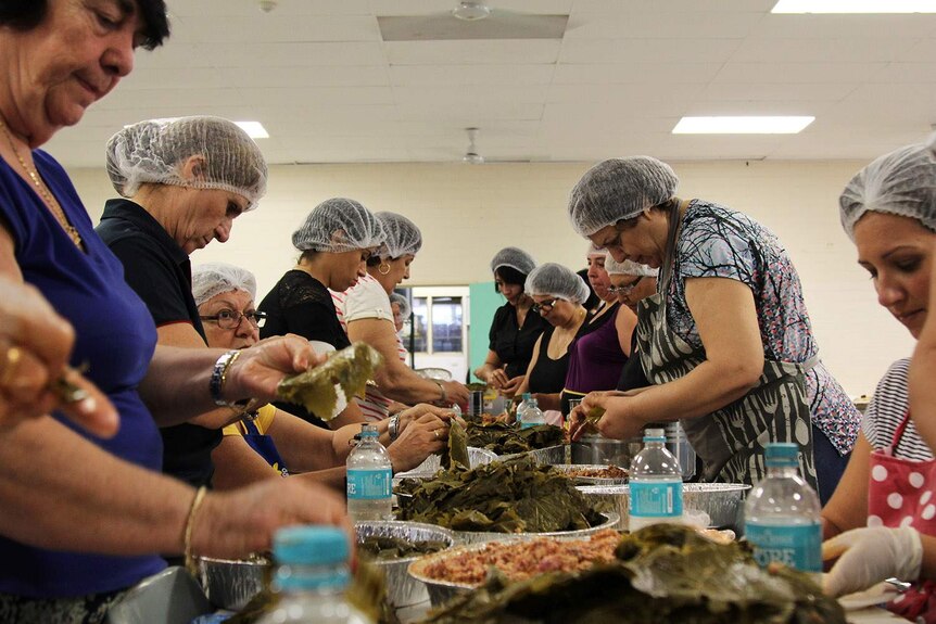a line of women making dolmades