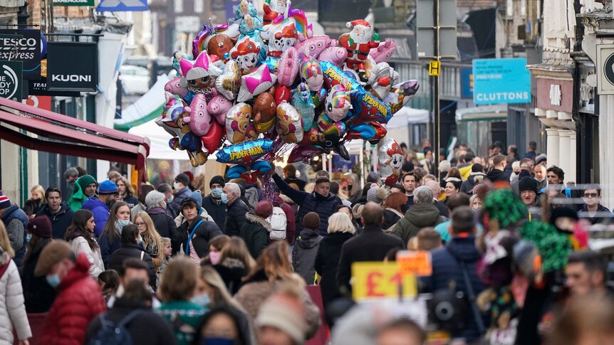 A crowd of people walk down a busy shopping street in England