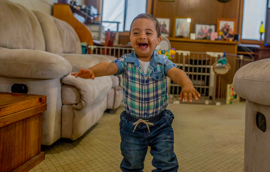 Daniel, a two-year-old boy with Down syndrome, running in his lounge room with a big smile