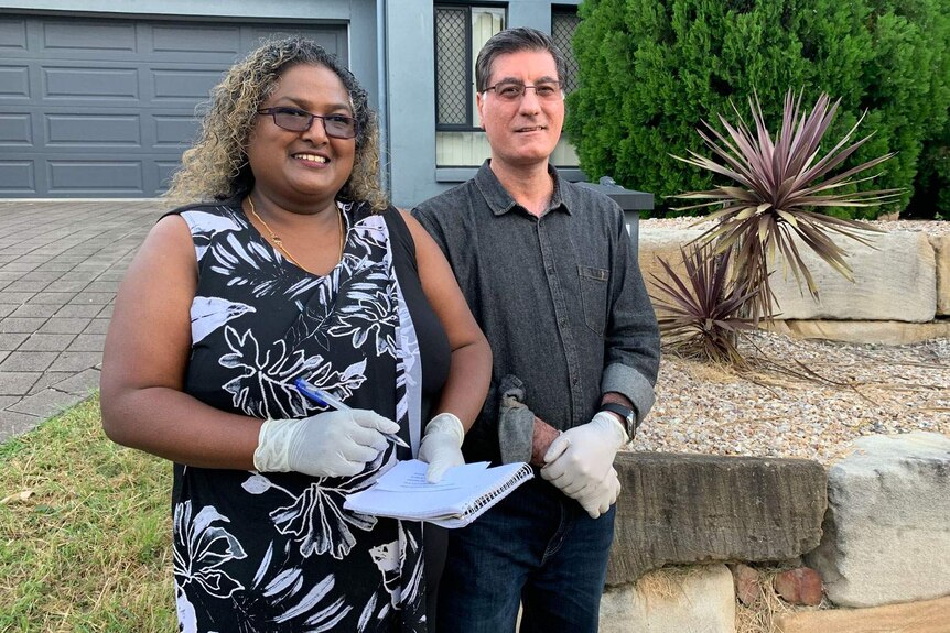 Residents Vicky and Siamak Mohajerin stand outside their home at Ipswich, west of Brisbane.