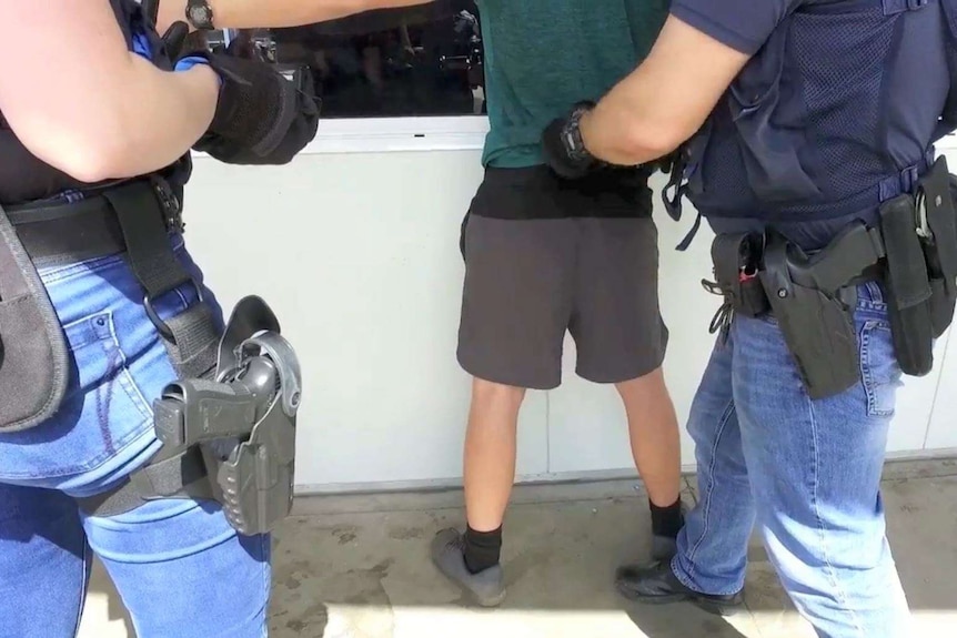 Border force officials search a worker up against a wall at a strawberry farm in Perth.