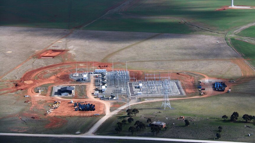 A electricity substation sits near turbines on a farm.