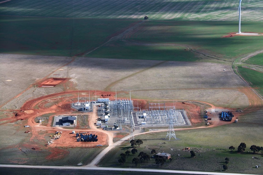 A electricity substation sits near turbines on a farm.