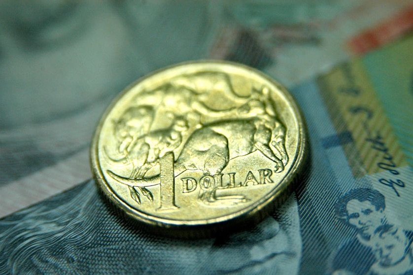 Australian one dollar coin sits on an Australian 20 dollar and 50 dollar note