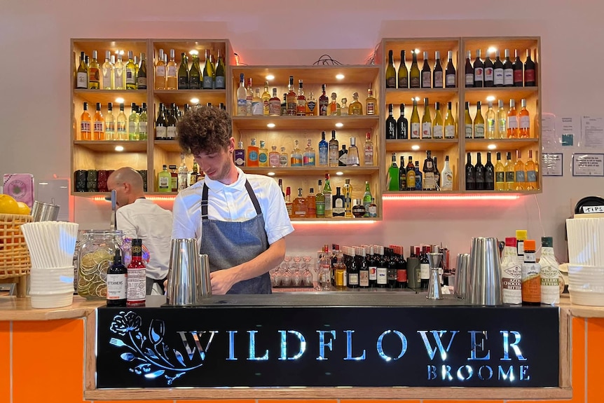 shelves of alcohol behind man 