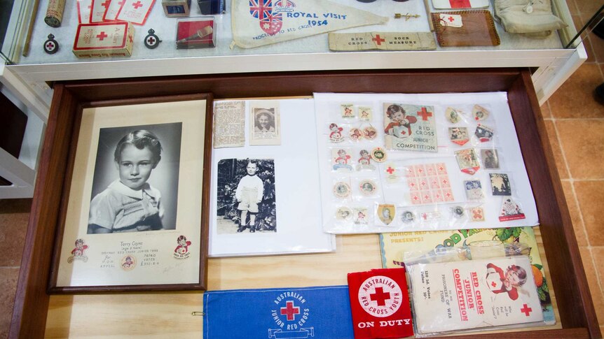 A drawer filled with Red Cross patches, photos and pins.