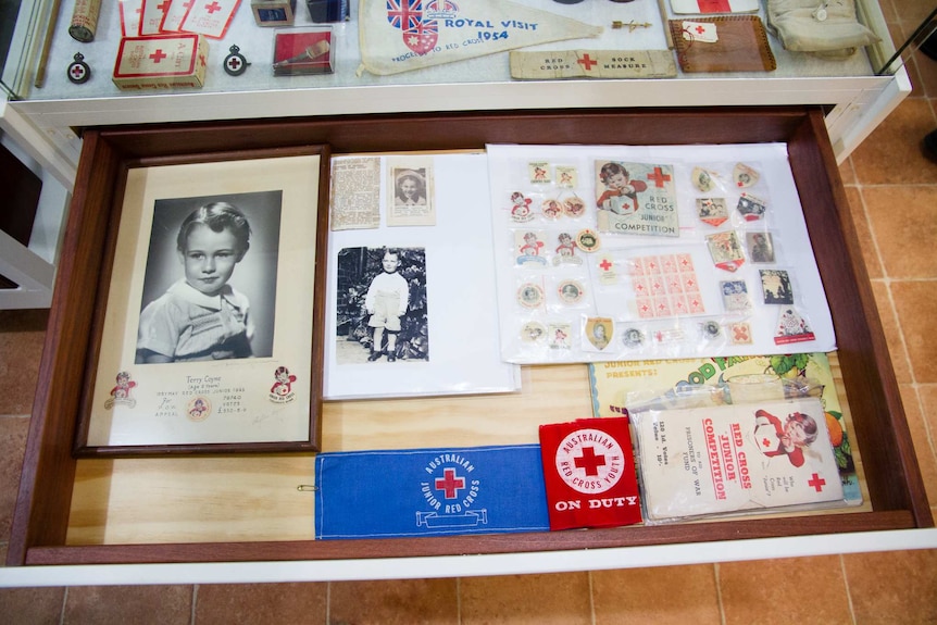 A drawer filled with Red Cross patches, photos and pins.