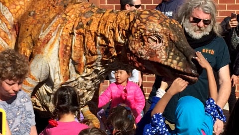 Children play with a dinosaur outside the WA Museum