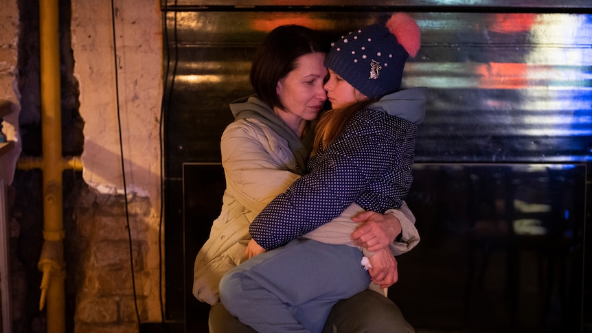 A woman hugs a young child in Kyiv, Ukraine after Russia invaded. Both look sad.
