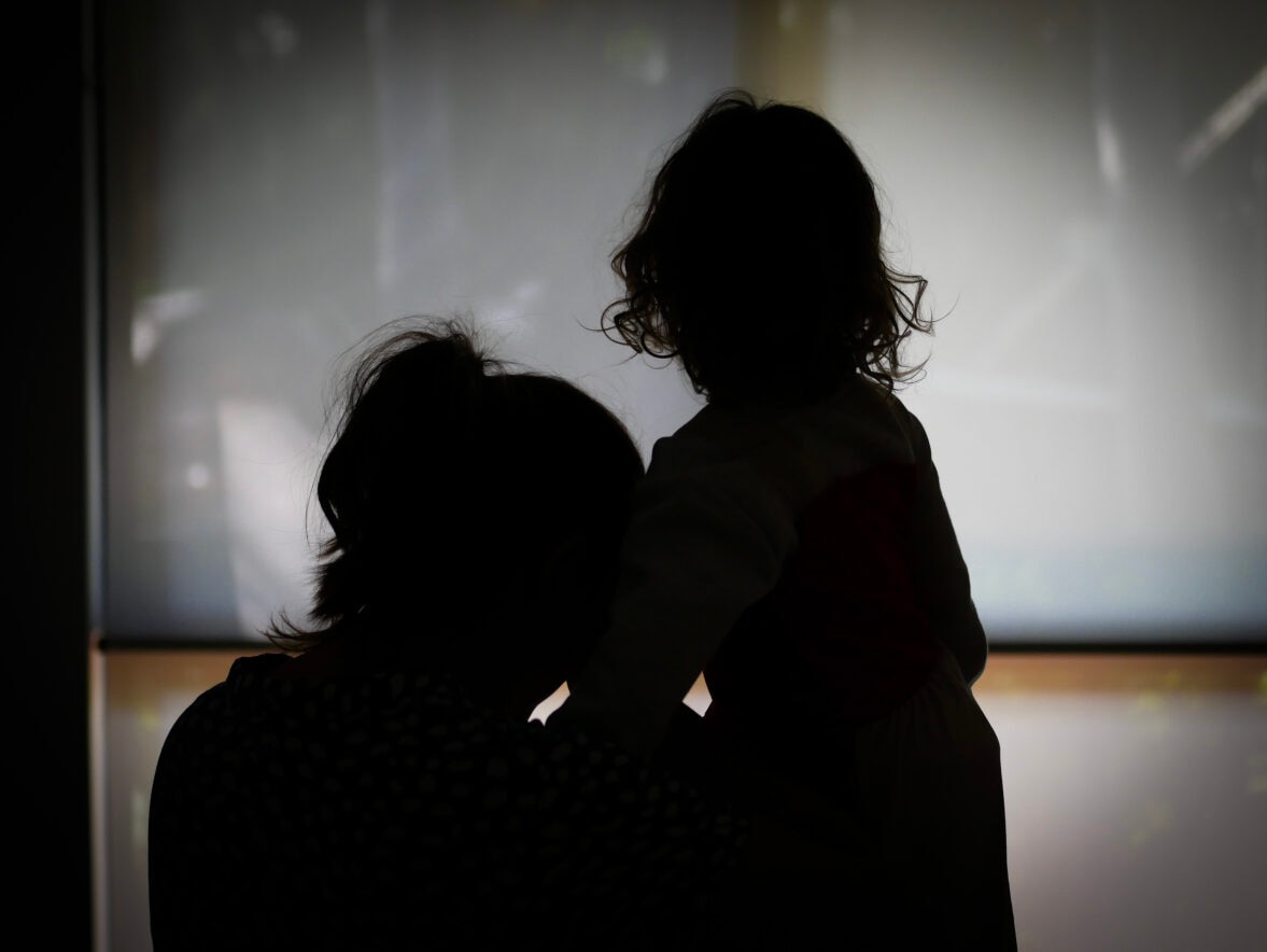 The silhouette of a woman leaning and holding a child.