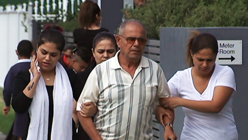 An older man and three young women walk along the street.