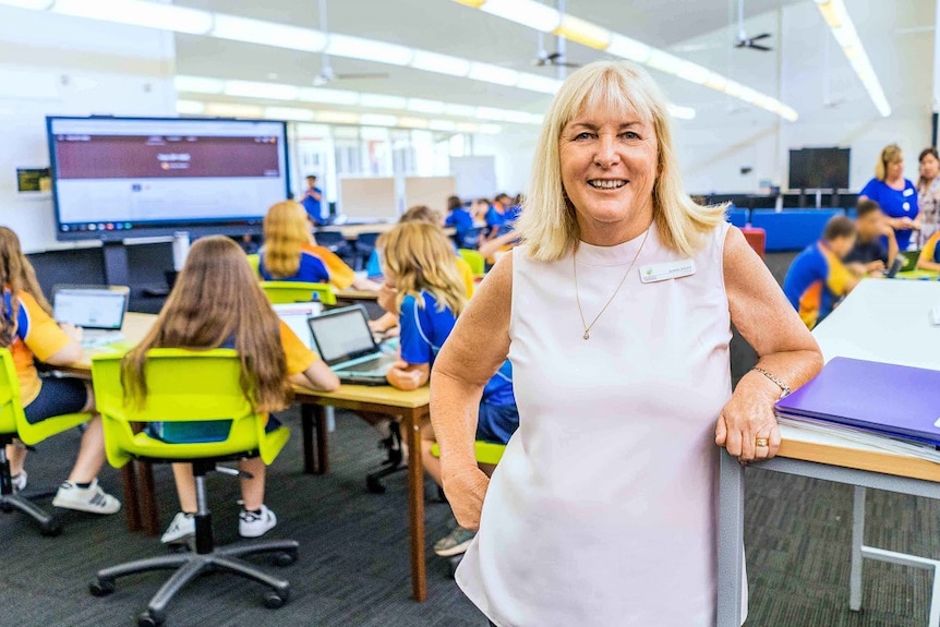 A woman standing in a classroom full of students.