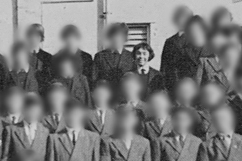 A black and white photo of a large group of children with all but one of their faces blurred.