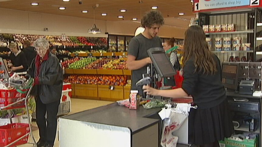 Customer being served at checkout of small supermarket