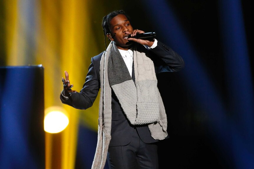 A$AP Rocky sings on stage in a suit with a scarf around his next
