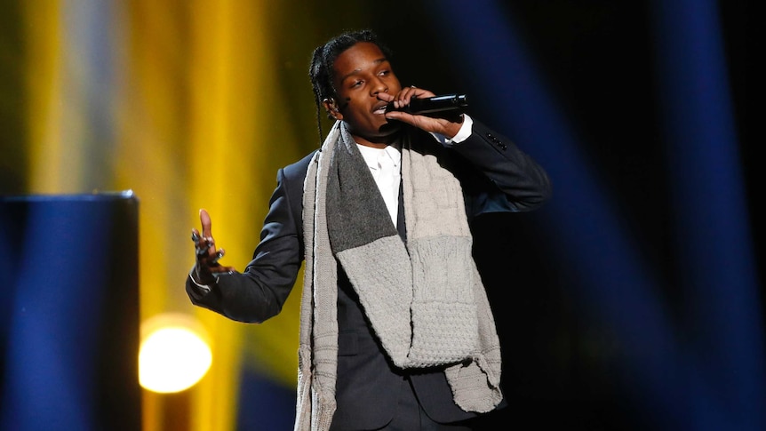 A$AP Rocky sings on stage in a suit with a scarf around his next