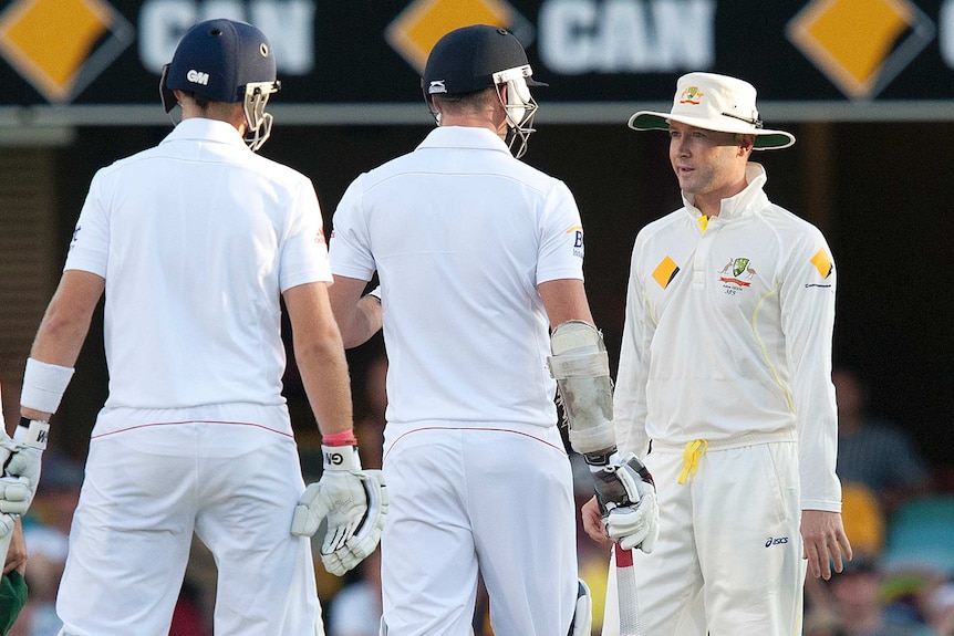 Michael Clarke speaks to James Anderson while another England batsman looks on during play in a Test match.