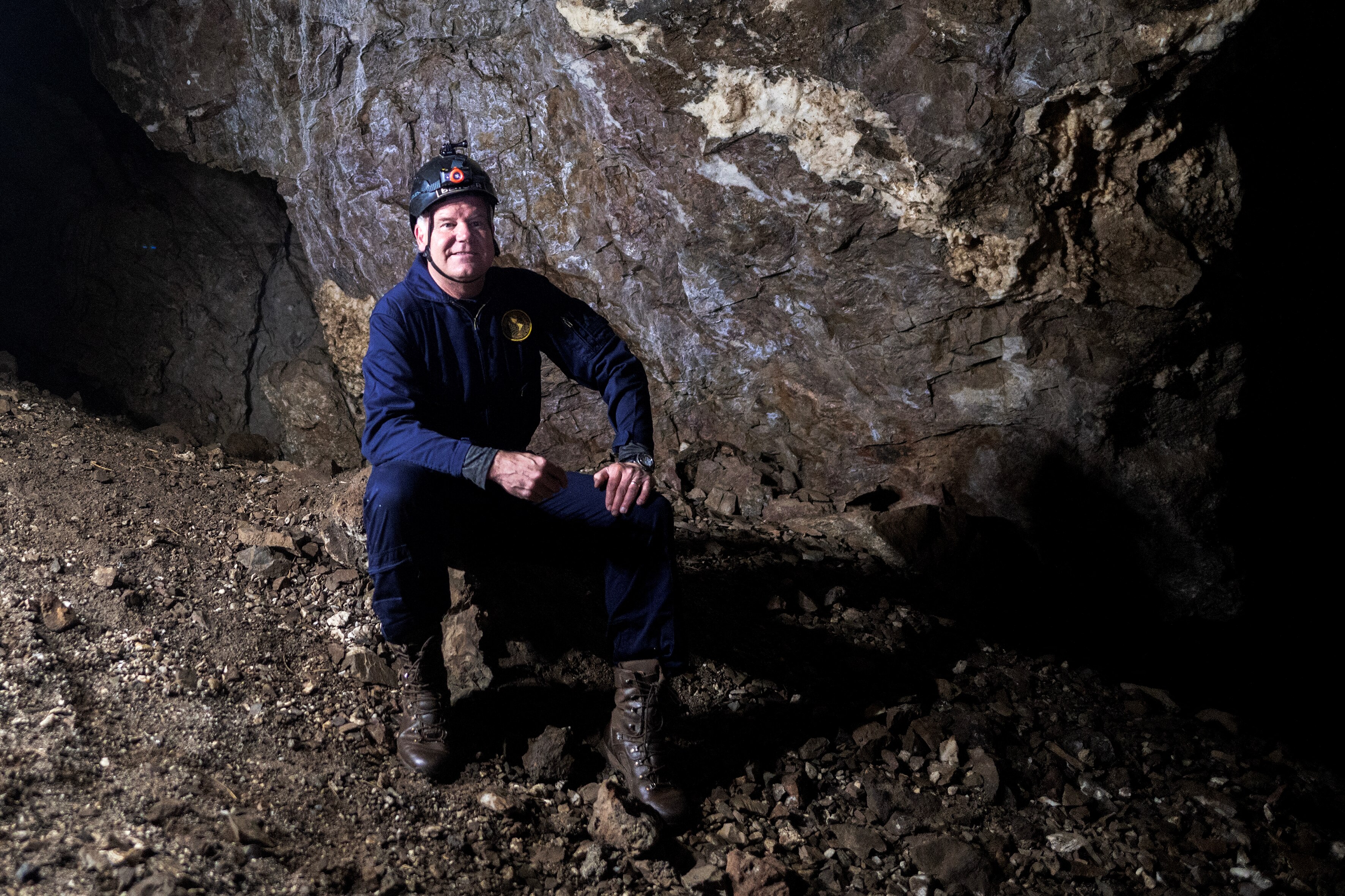 A man sitting on a rock inside a cave. 