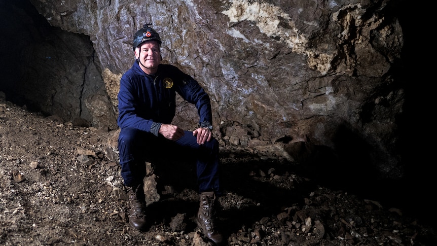 A man sitting on a rock inside a cave. 