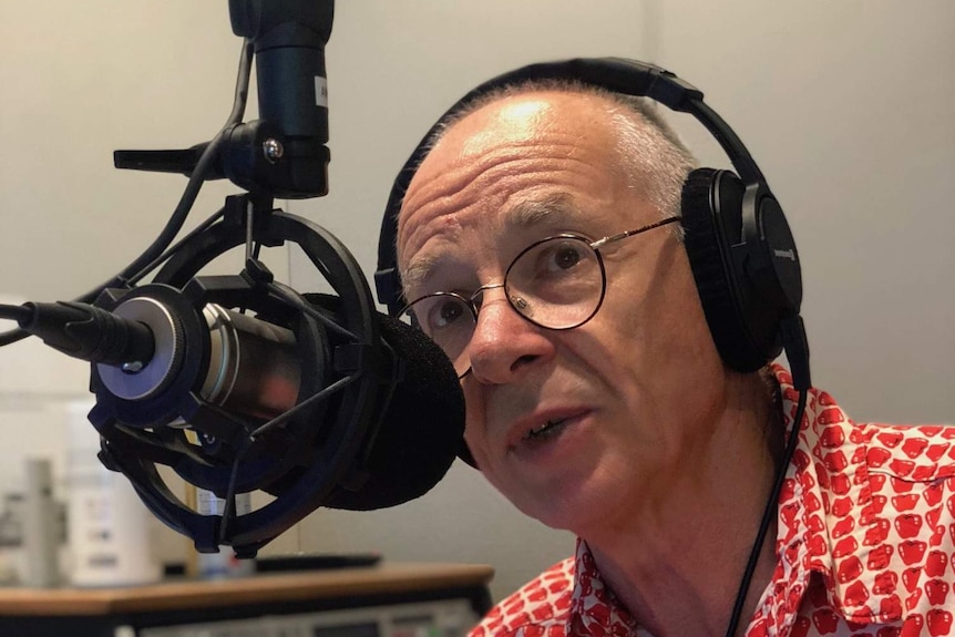 A man wearing large headphones speaks into a microphone.