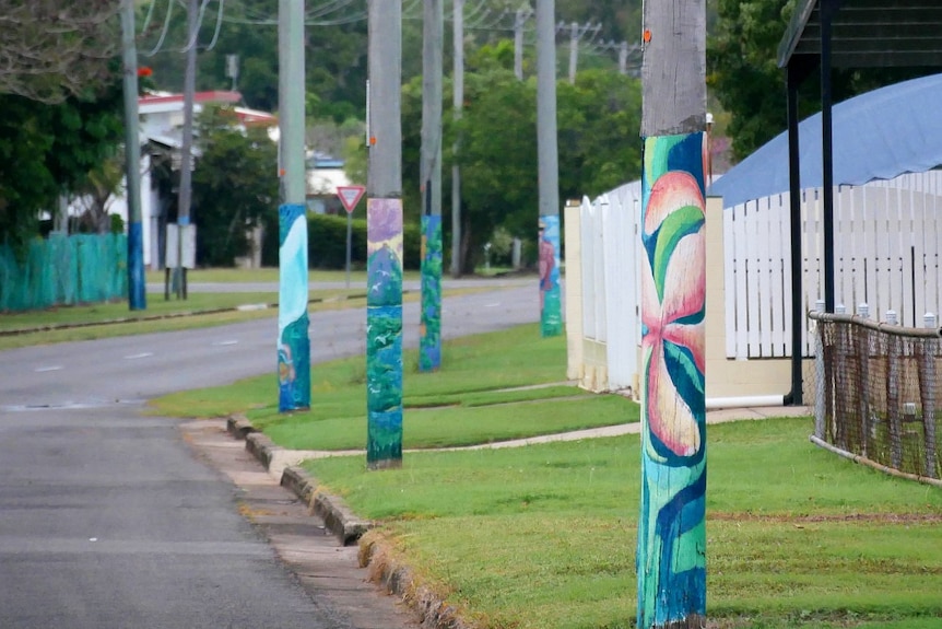 Painted power poles line the roadside on a quiet street