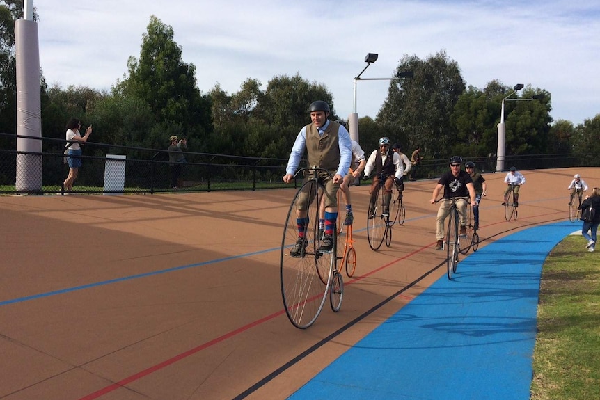 Cyclists race Penny Farthings at the Brunswick velodrome.
