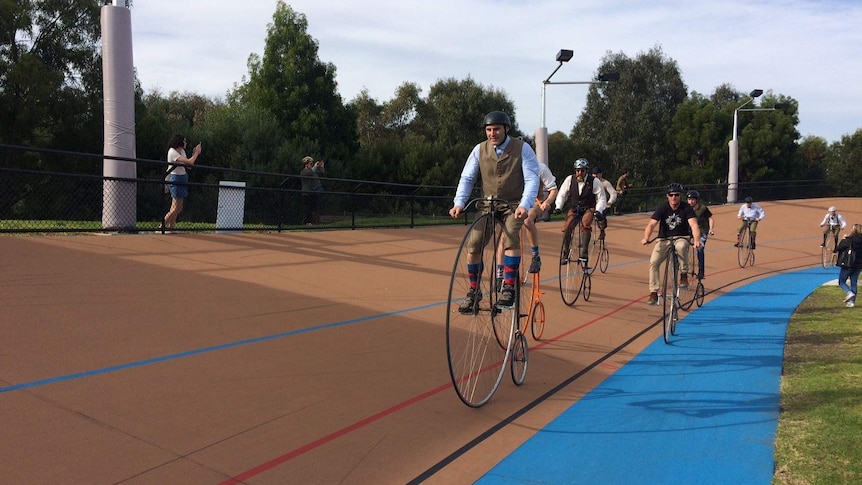 Cyclists race Penny Farthings at the Brunswick velodrome.