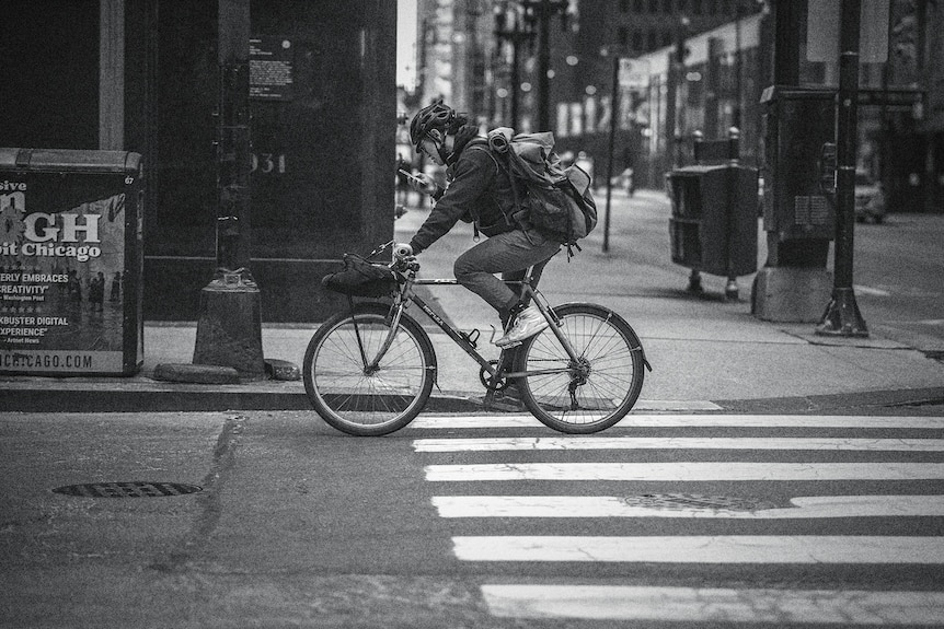 a bike messenger speeding down a street, with lights blurring