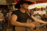Lee Kernaghan holds a guitar in a scene from the music video for his song, Boys From the Bush