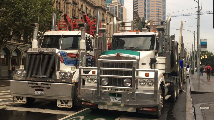 Two trucks parked side by side on a road in Melbourne.