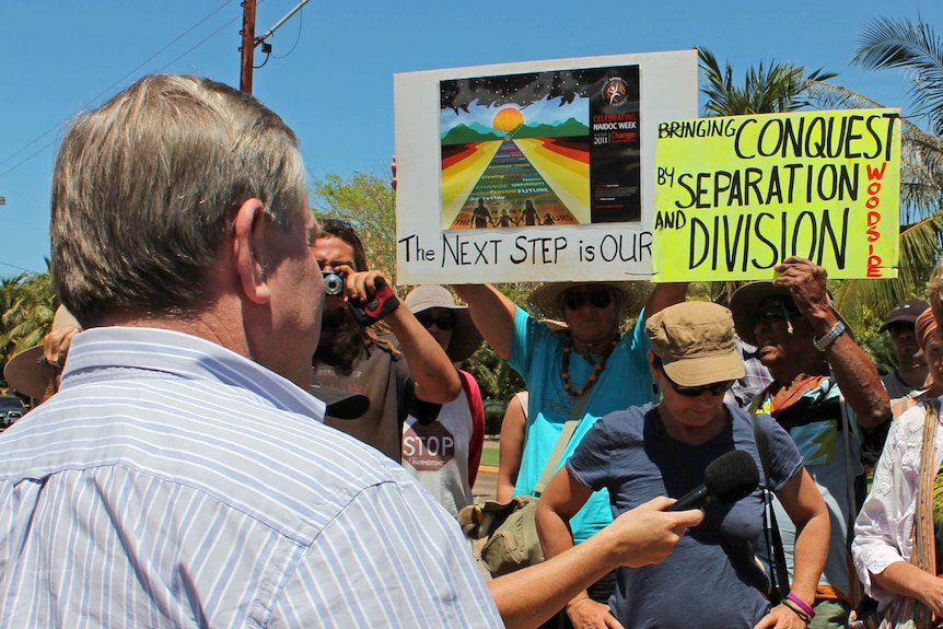 Premier Barnett meets protestors carrying signs