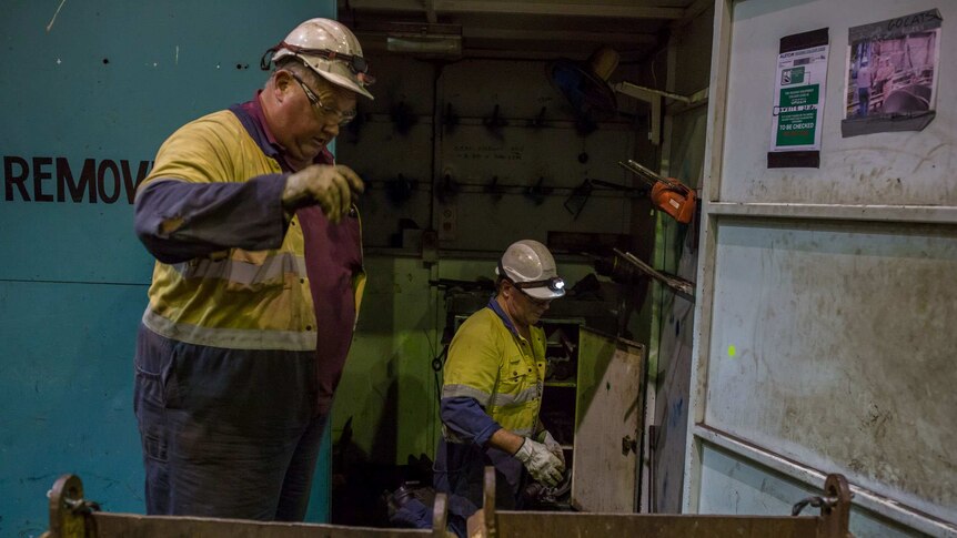 Workers toss parts into bins as they begin dismantling their workplace