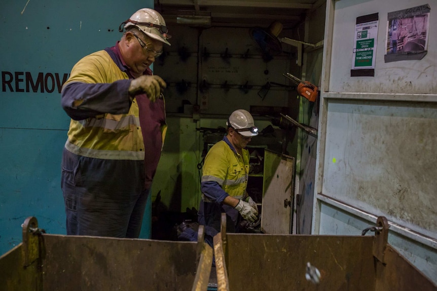 Workers toss parts into bins as they begin dismantling their workplace