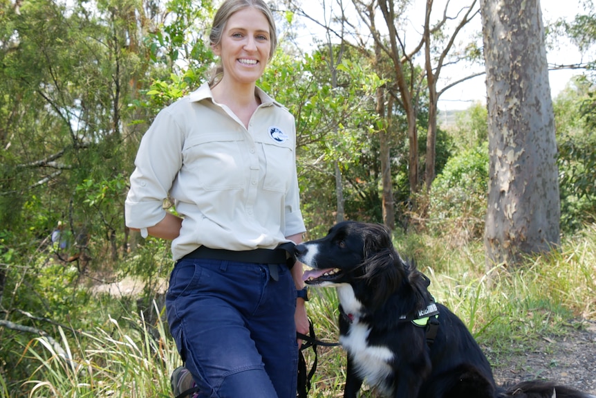 A woman holding a dog on a lead in bushland