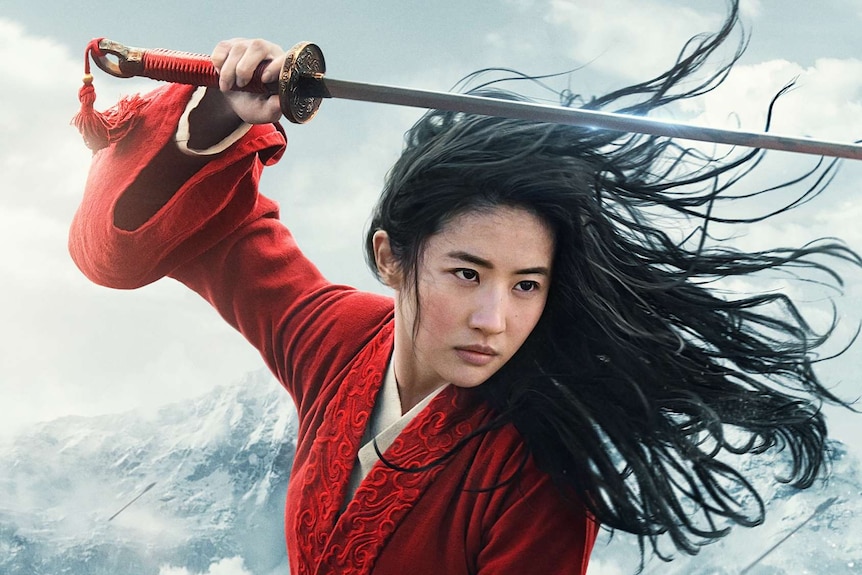 A woman with wind-swept hair looks fiercely off-camera, holding a sword about her head.