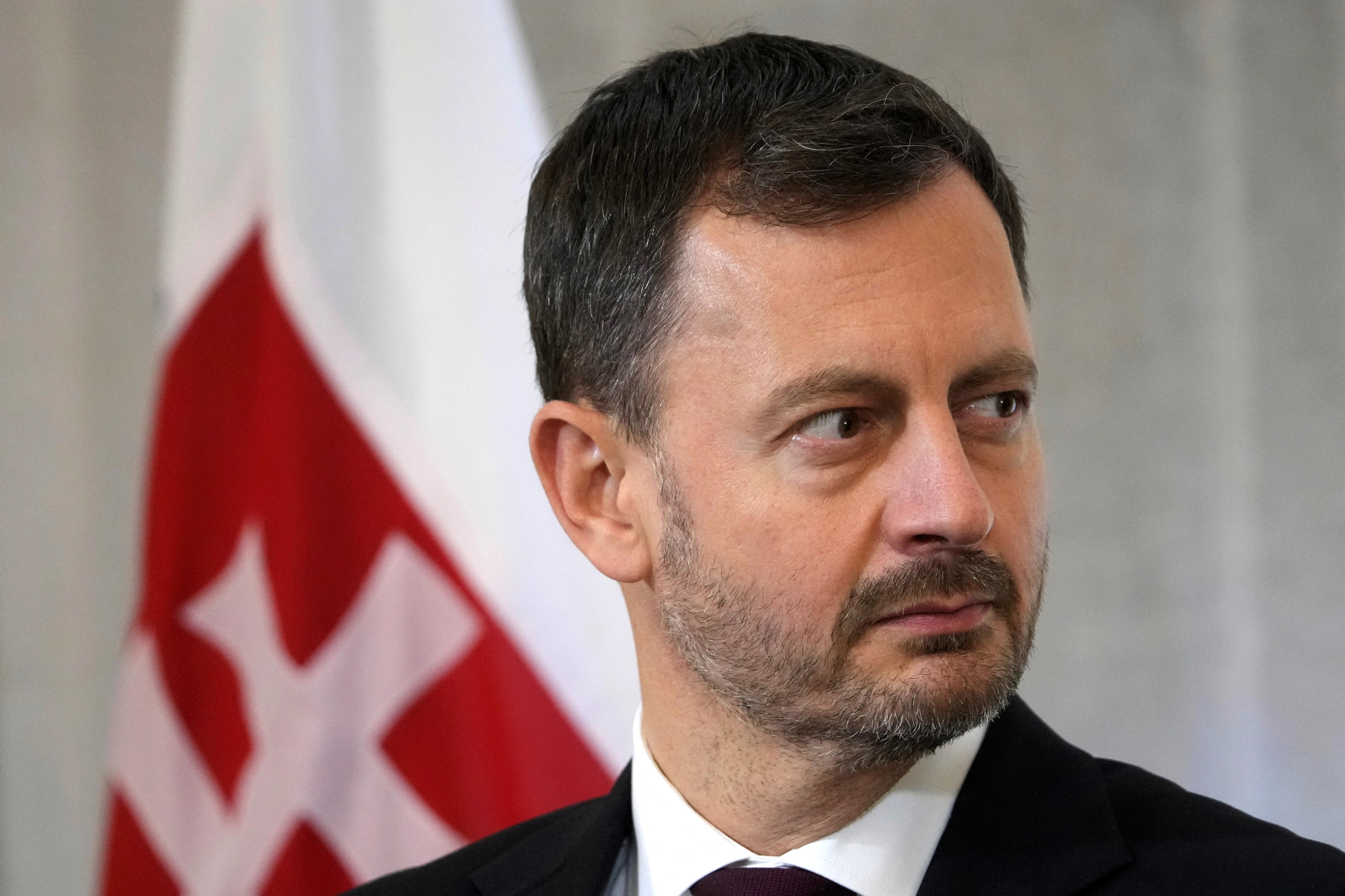 A middle-aged man with short dark hair and a short beard stands in front of a Slovakian flag.