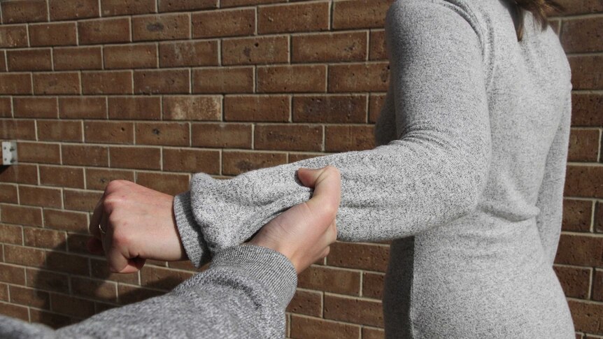 a man grabbing a woman's hand forcefully