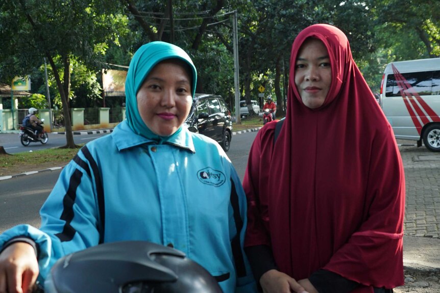 Passenger Sofiyah standing beside Ojesy driver Wiwik Daryanti.