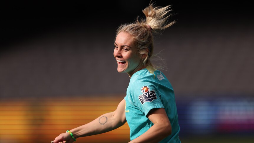 A footballer smiles during training, as her ponytail flies up in the air.