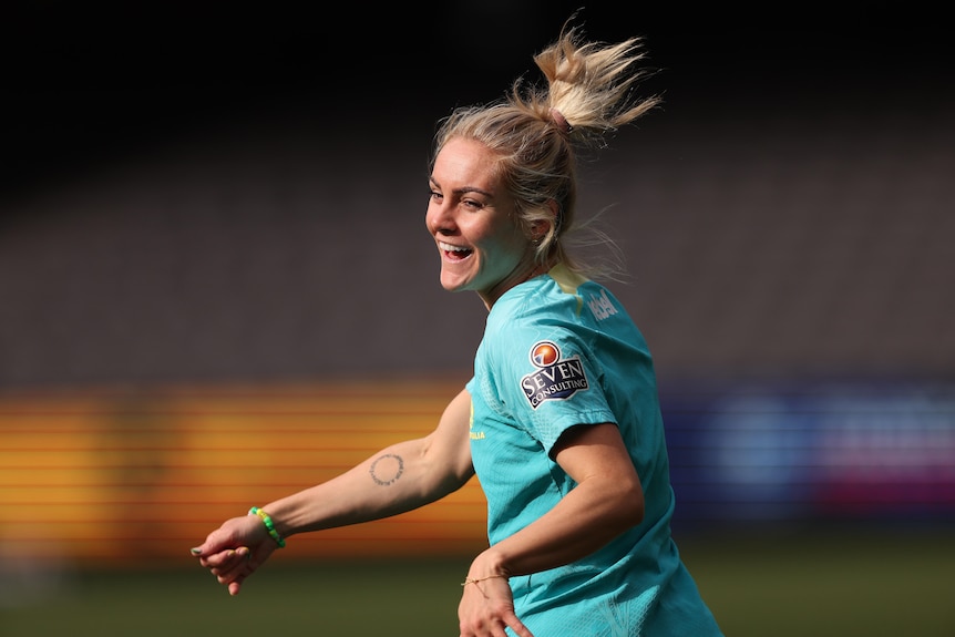 A footballer smiles during training, as her ponytail flies up in the air.