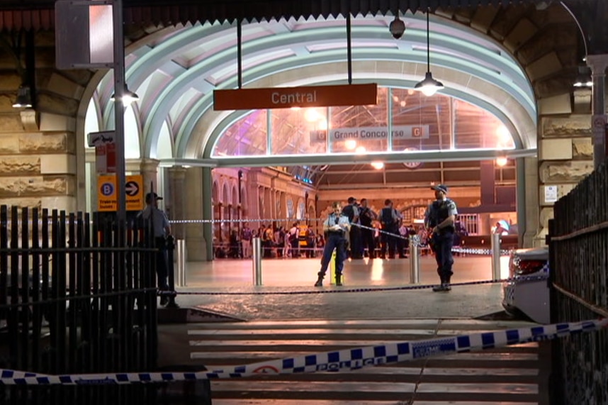 A police officer standing in front of the entrance to a train station.