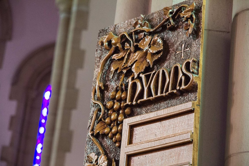 A wooden board inside a church reads 'hymns'