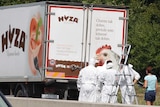 Forensic officers stand by a truck containing a large number of dead migrants